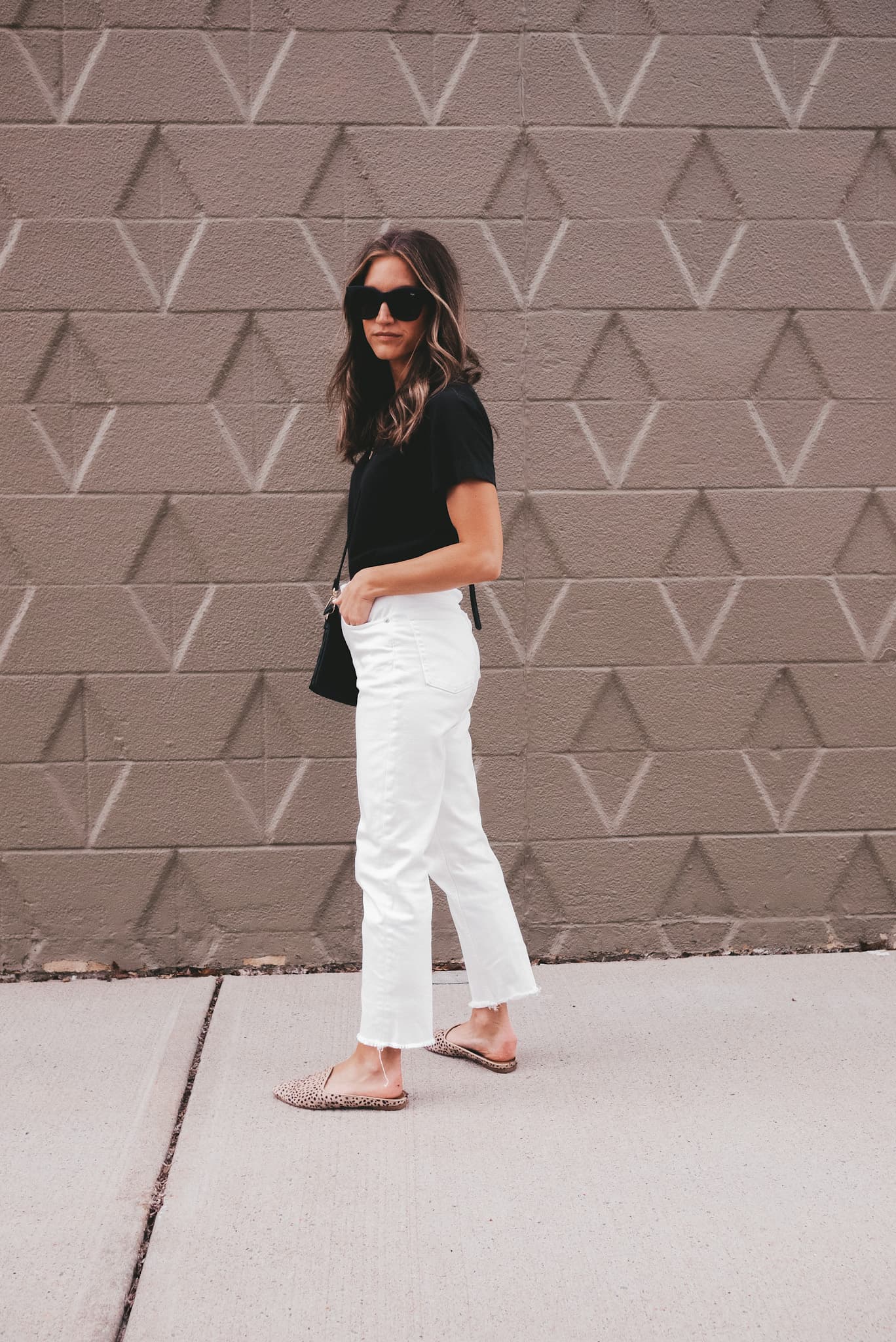 ashley wearing an Everlane black tee, white Everlane straight leg jeans, and Target leopard mules