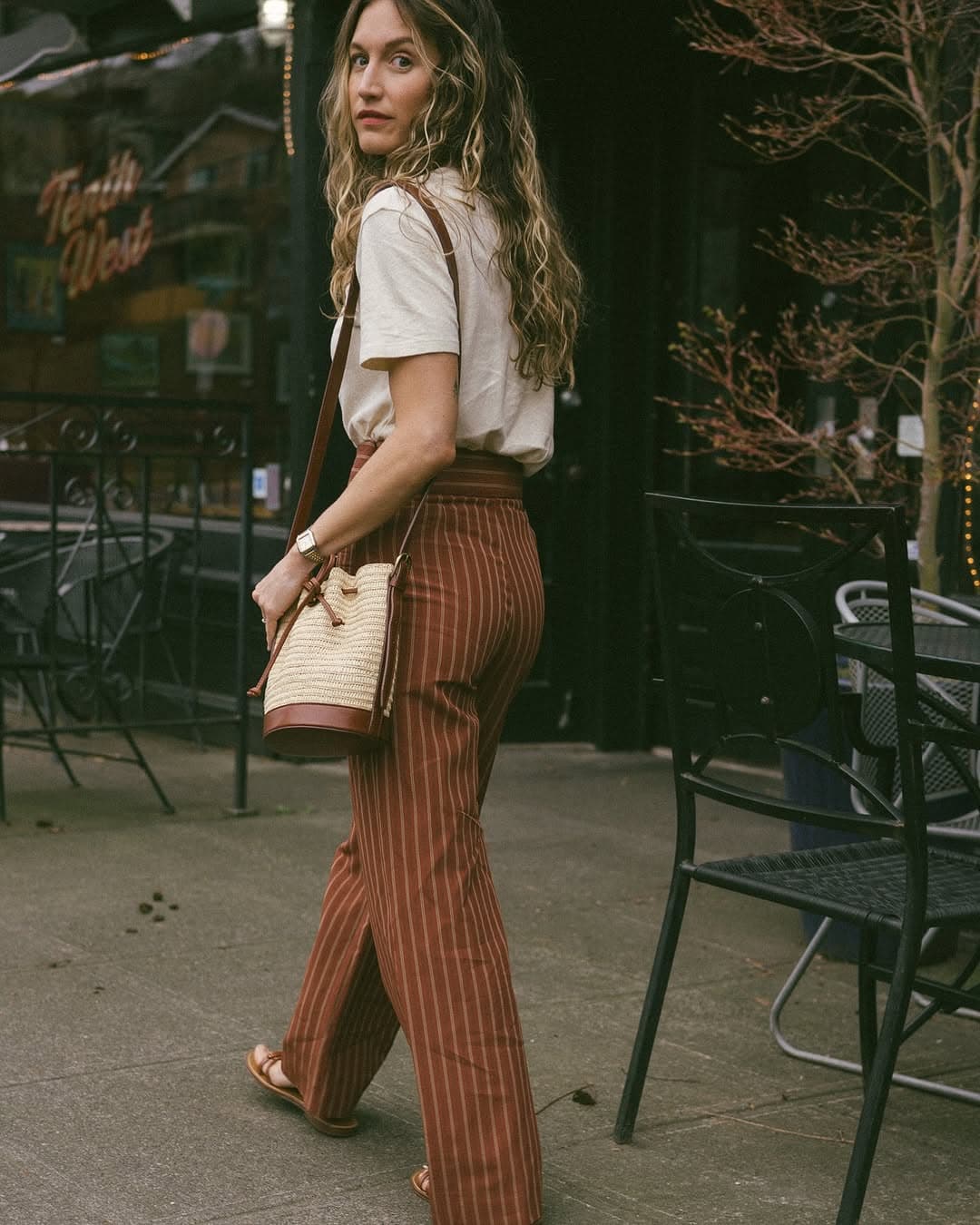Brown striped trousers with a white tee and raffia bucket bag