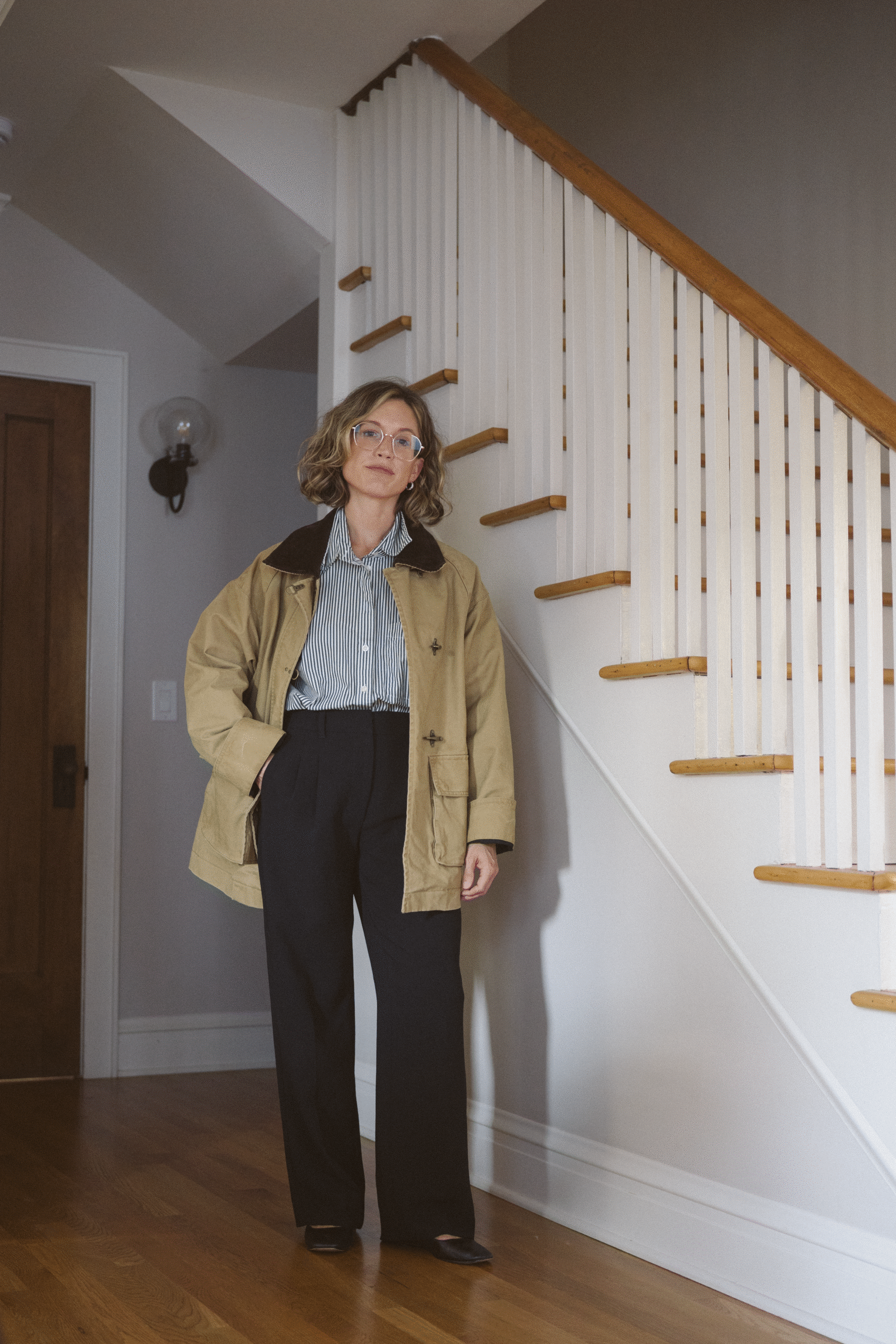 barn jacket outfit with a striped button down, black trousers, and black mary jane ballet flats