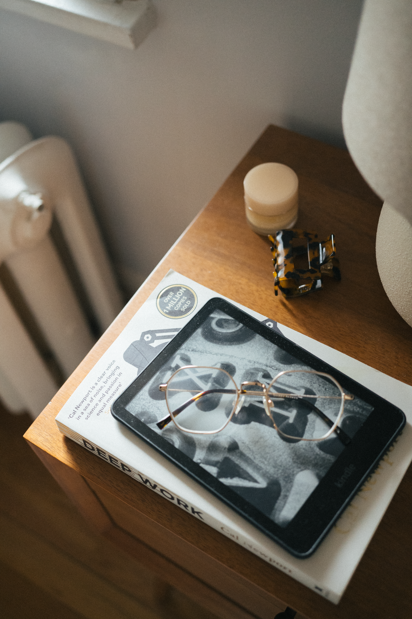 a nightstand with a book and a Kindle on top 