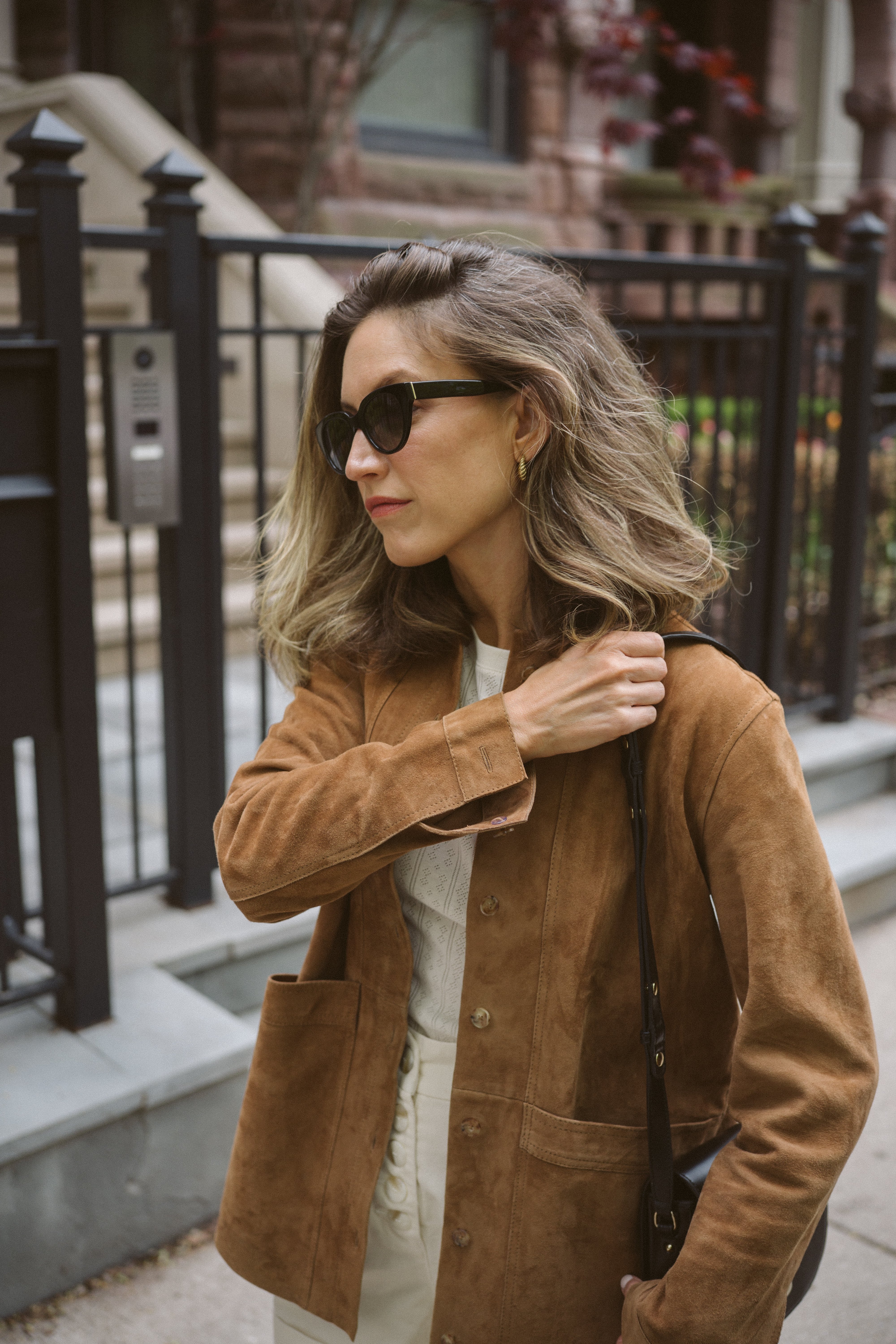 ashley wearing a suede leather jacket, white shorts, and leopard print ballet flats on a city street 